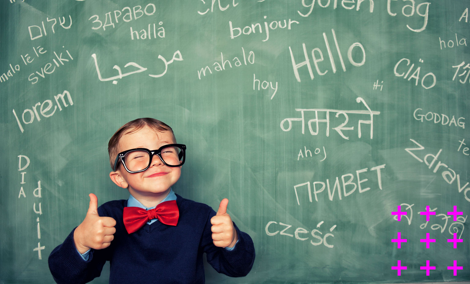 Menino sorri na frente de uma lousa com palavras em diversos idiomas.