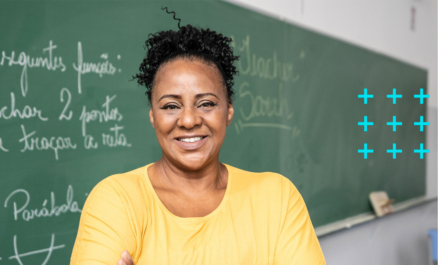 Professora dentro da sala de aula sorrindo.