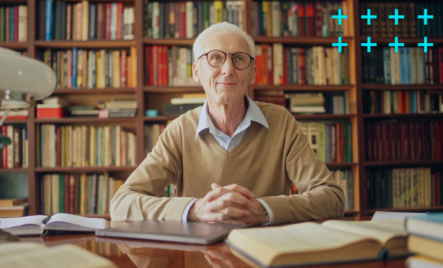 Homem idoso sentado em uma biblioteca.