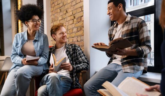 Três estudantes conversando na biblioteca da escola.