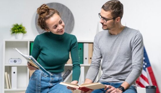 dois alunos estudando juntos em um ambiente de aprendizado, sorrindo e interagindo com livros e materiais de estudo.