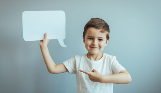 menino segurando um balão de fala de papel e apontando para ele.