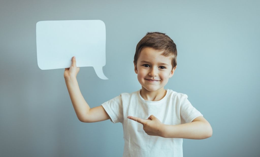 menino segurando um balão de fala de papel e apontando para ele.